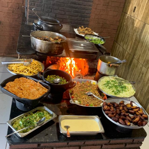 Buffet no fogão a lenha aceso com labaredas no D'Família
